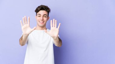 Mor arka planda izole edilmiş genç beyaz adam on numarayı elleriyle gösteriyor..