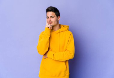 Mor arka planda izole edilmiş genç beyaz adam bir strateji planlıyor, bir işin nasıl olacağını düşünüyor..