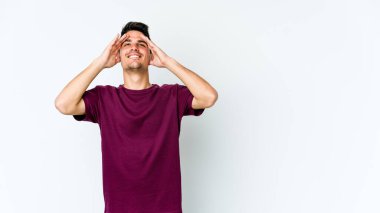 Beyaz arka planda izole olmuş genç beyaz bir adam ellerini başının üstünde tutarak neşeyle gülüyor. Mutluluk kavramı.