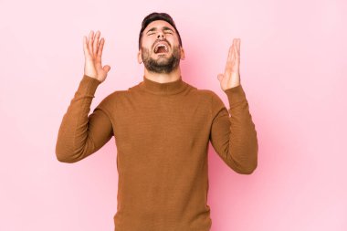 Pembe arka planda genç beyaz bir adam izole edilmiş, gökyüzüne haykırıyor, yukarı bakıyor, hayal kırıklığına uğramış..