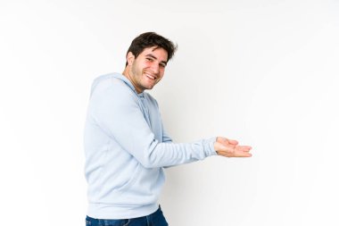 Beyaz arka planda izole edilmiş genç bir adam avucunun içinde bir kopya alanı tutuyor..