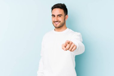 Mavi arka planda izole edilmiş genç beyaz adam öne bakan neşeli gülümsemeler.