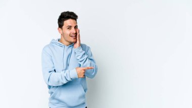 Beyaz arka planda izole edilmiş genç beyaz bir adam bir dedikodu söylüyor, bir haber sunuyor..