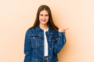 Beyazlı genç bir kadın bej arka planda izole edilmiş. İşaret parmaklarıyla bir fotokopi alanını işaret ederek şok olmuş..