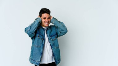 Beyaz arka planda izole edilmiş genç beyaz bir adam kulaklarını elleriyle kapatıyor..