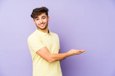 Mor arka planda izole edilmiş genç bir Arap adam bir palmiyenin üzerinde bir kopya alanı tutuyor..