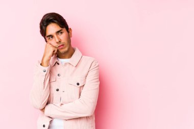 Pembe arka planda yalnız poz veren beyaz bir genç üzgün ve dalgın bir şekilde fotokopi odasına bakıyor..