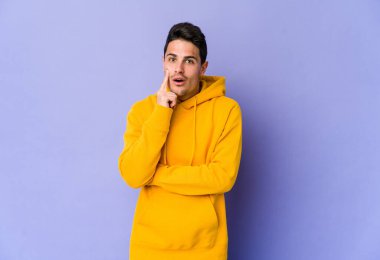 Mor arka planda soyutlanmış genç beyaz bir adam. Yaratıcılık kavramı hakkında harika bir fikri var..