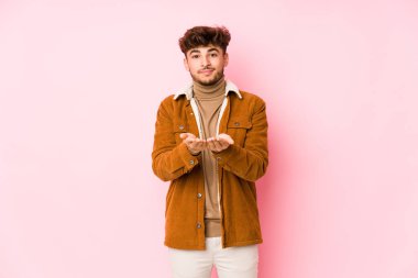 Pembe arka planda yalnız poz veren genç bir Arap.