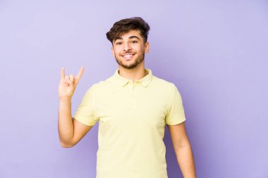 Mor arka planda izole edilmiş genç bir Arap adam boynuzları bir devrim konsepti olarak gösteriyor..