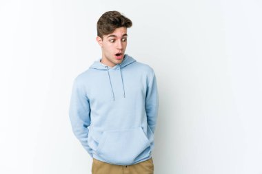 Beyaz arka planda izole edilmiş genç beyaz adam gördüğü bir şey yüzünden şoka uğruyor..