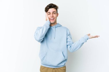 Beyaz arka planda izole edilmiş genç beyaz bir adam bir avuç içinde fotokopi alanı tutuyor, el üstünde tutuyor. Şaşırmış ve mutlu..