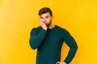 Sarı arka planda izole edilmiş genç, üzgün ve dalgın hisseden, kopyalama alanına bakan beyaz bir adam..