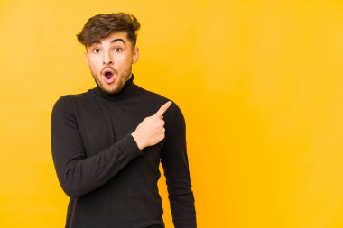 Sarı arka planda yalıtılmış genç bir Arap yan tarafı gösteriyor.