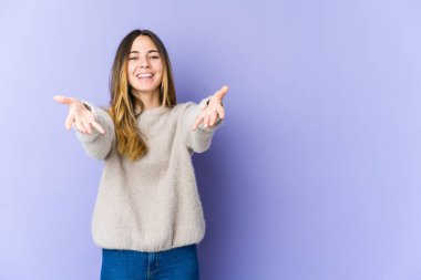 Mor arka planda izole edilmiş genç beyaz kadın kameraya sarıldığı için kendinden emin..