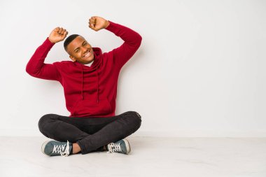 Yerde oturan genç latin adam izole edilmiş kollarını uzatıyordu, rahat duruyordu..