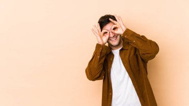 Bej arka planda izole edilmiş genç adam gözlerde sorun olmadığını gösteriyor.