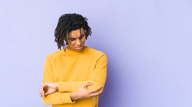 Genç siyah adam Rasta saç stili giyiyor. Dirsek masajı yapıyor. Kötü bir hareketin ardından acı çekiyor..