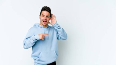 Beyaz arka planda izole edilmiş genç beyaz adam bir dedikoduyu dinlemeye çalışıyor..