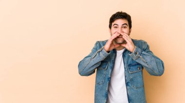 Genç adam bej arka planda izole edilmiş. Dedikodu yapıyor, bir şeyleri bildiriyor..