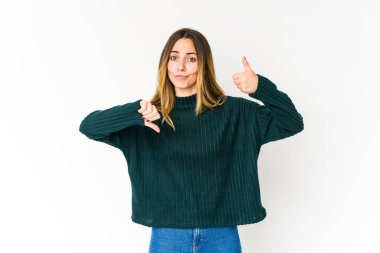 Beyaz arka planda izole edilmiş genç beyaz bir kadın baş parmağını kaldırıyor ve baş parmağını aşağı gösteriyor, zor seçim konsepti.