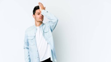 Beyaz arka planda izole edilmiş genç beyaz bir adam bir şeyi unutuyor. Alnına avuç içi ve gözlerini kapayarak vuruyor..