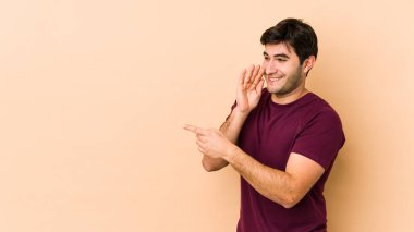 Genç adam bej arka planda izole edilmiş. Dedikodu yapıyor, bir şeyleri bildiriyor..