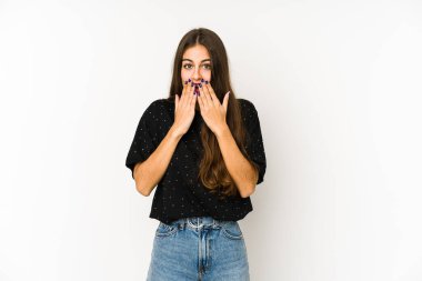 Beyaz arka planda izole edilmiş genç beyaz kadın şok olmuş, elleri ağızda, yeni bir şey keşfetmeye hevesli..