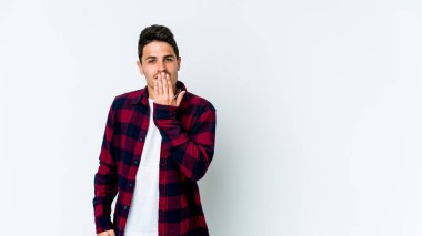 Beyaz arka planda izole edilmiş genç beyaz adam şok olmuş, ağzı ellerle kaplanmış, yeni bir şey keşfetmeye hevesli..