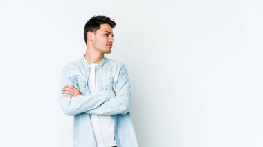 Beyaz arka planda izole edilmiş genç beyaz bir adam şüpheli, belirsiz, seni muayene ediyor..