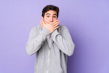 Mor arka planda izole edilmiş genç adam elleriyle ağzını kapatırken şok oldu..