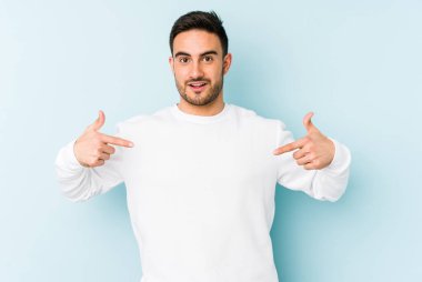 Kafkasyalı genç adam mavi arka planda izole edildi. Parmakları aşağıda, olumlu bir his var..