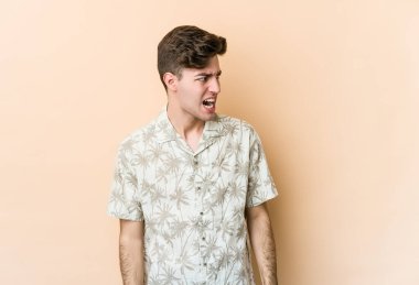 Beyazlı genç bir adam bej arka planda izole edilmiş çok kızgın, öfkeli, hayal kırıklığına uğramış.