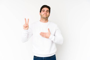 Beyaz arka planda yaşayan genç bir adam yemin ediyor, elini göğsüne koyuyor..