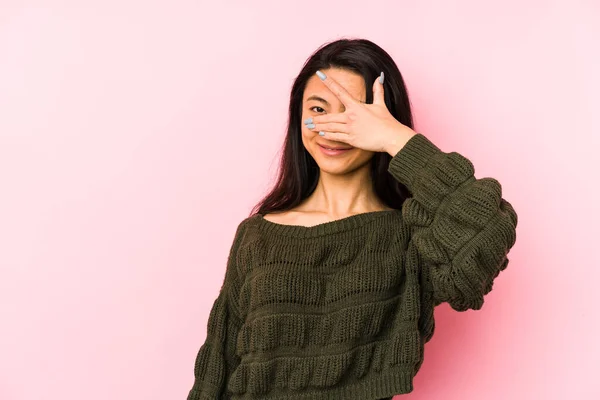 年轻的中国女人用粉红的背景用手指对着相机眨眼 尴尬地蒙着脸 — 图库照片