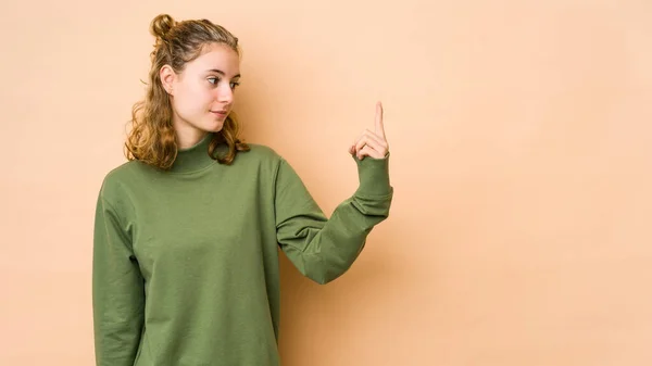 Jonge Kaukasische Vrouw Geïsoleerd Beige Achtergrond Wijzend Met Vinger Naar — Stockfoto