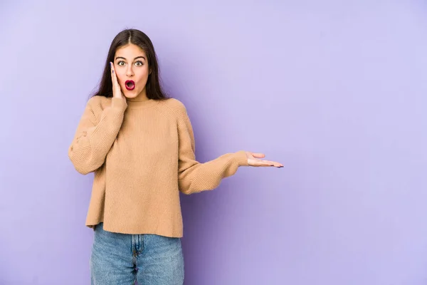 Jovem Mulher Caucasiana Isolado Fundo Roxo Impressionado Segurando Espaço Cópia — Fotografia de Stock