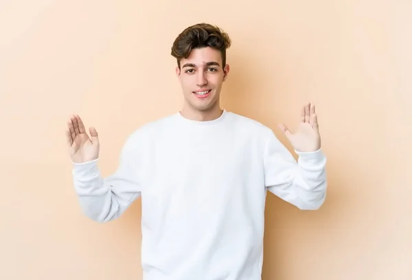 Young Caucasian Man Isolated Beige Background Holding Something Little Forefingers — Stock Photo, Image