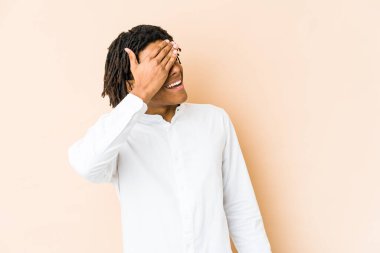 Genç Afrikalı Amerikalı Rasta adam elleriyle gözlerini kapatıyor, gülümseyerek bir sürpriz bekliyor..