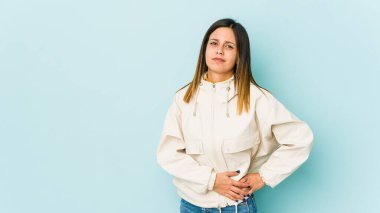 Mavi arka planda izole edilmiş genç bir kadın. Karaciğer ağrısı, mide ağrısı var..