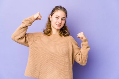 Mor arka planda genç beyaz bir kadın zaferden sonra yumruğunu kaldırıyor, kazanan konsept.