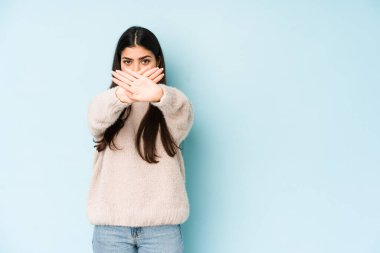 Mavi arka planda izole edilmiş genç Hintli kadın inkar jesti yapıyor.