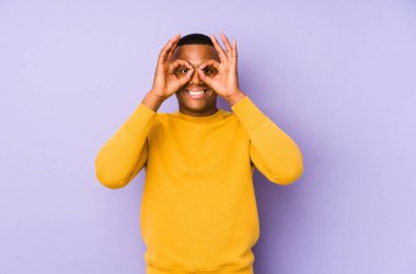 Mor arka planda izole edilmiş genç latin adam gözlerde sorun olmadığını gösteriyor.