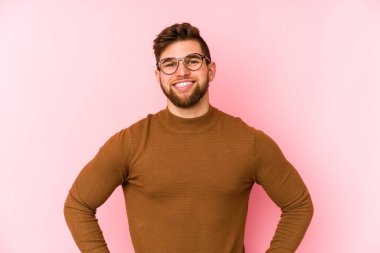 Pembe arka planda izole edilmiş beyaz bir adam. Kendine güveniyor. Kalçaları tutuyor..