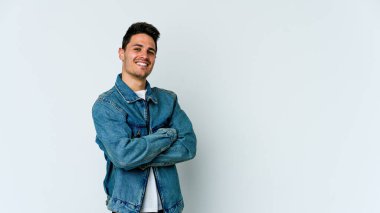 Beyaz arka planda kendini güvende hisseden, kararlılıkla kollarını kavuşturan beyaz tenli genç bir adam..