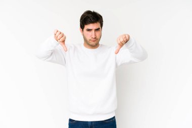 Beyaz arka planda izole edilmiş genç bir adam, hoşlanmadığı bir hareket gösteriyor, başparmakları aşağıda. Anlaşmazlık konsepti.