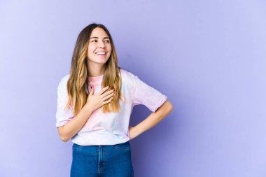 Mor arka planda soyutlanmış beyaz bir kadın. Gülüyor, elini kalbe koyuyor, mutluluk kavramını koruyor..