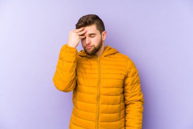 Mor arka planda izole edilmiş genç bir adam. Başı ağrıyor, yüzüne dokunuyor..
