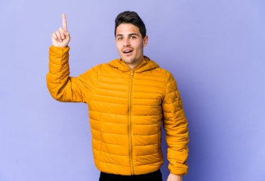 Mor arka planda soyutlanmış genç beyaz bir adam. Yaratıcılık kavramı hakkında harika bir fikri var..