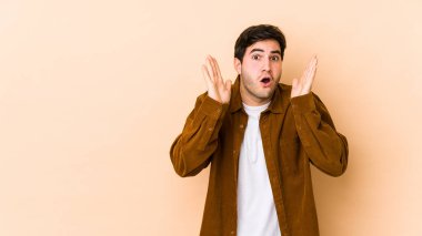 Bej arka planda izole genç adam şaşırdı ve şok oldu..